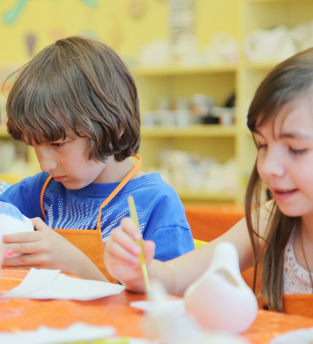 Children painting ceramic figures together in an art class
