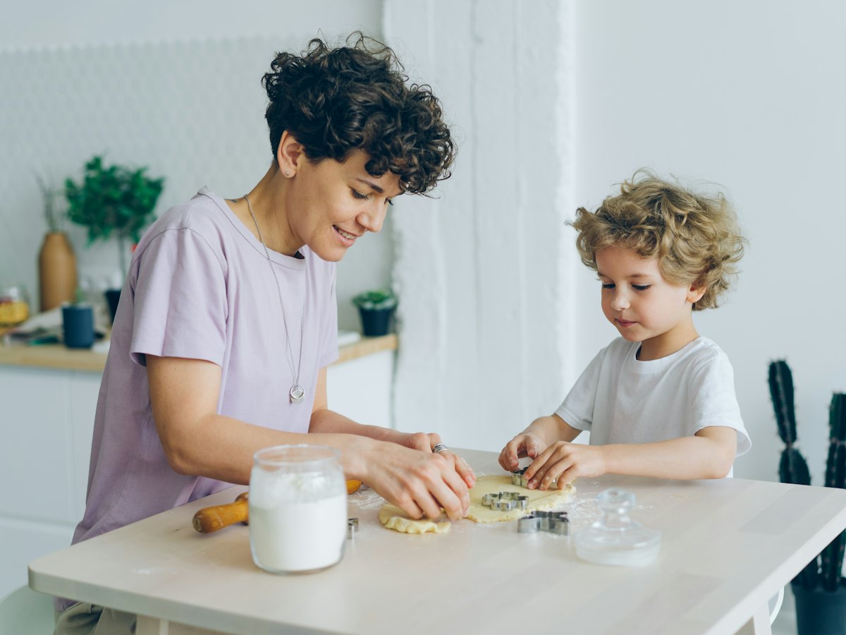 A mom and her young son cutting out cookies together