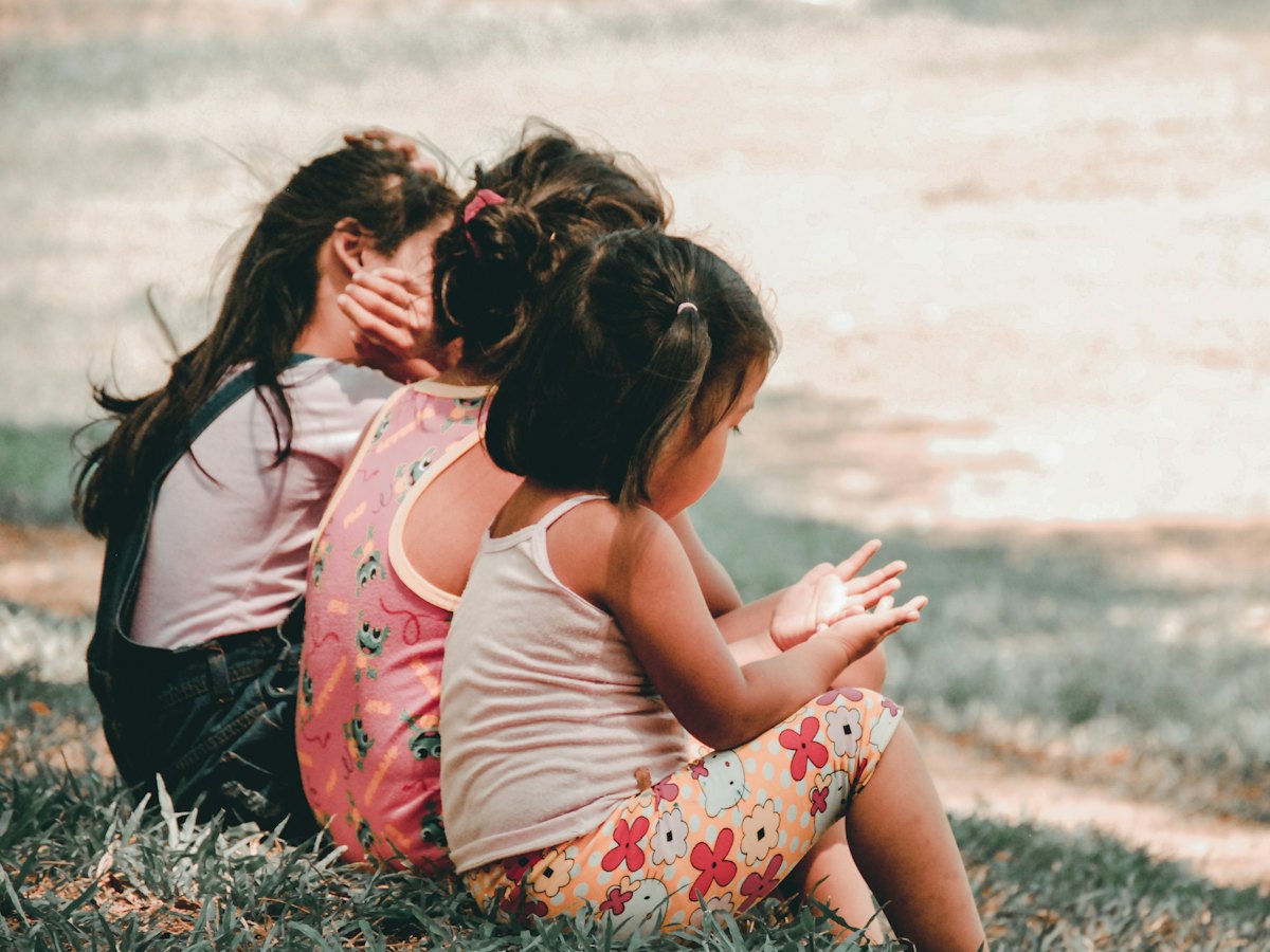 Three girls sitting close together on the grass