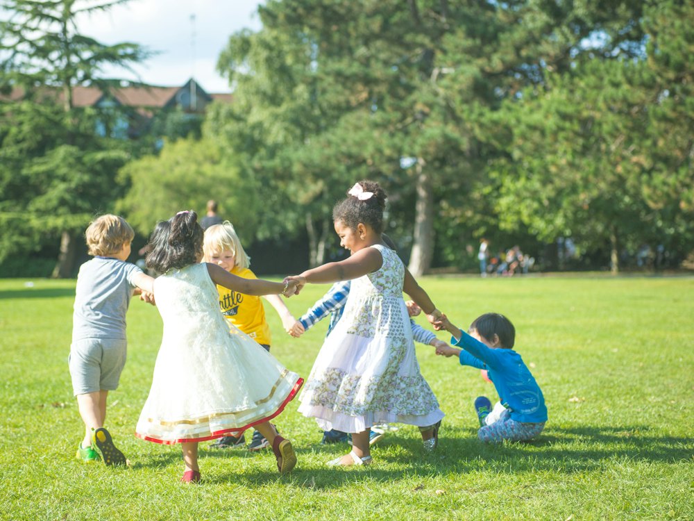 Children holding hands in a circle on a park lawn