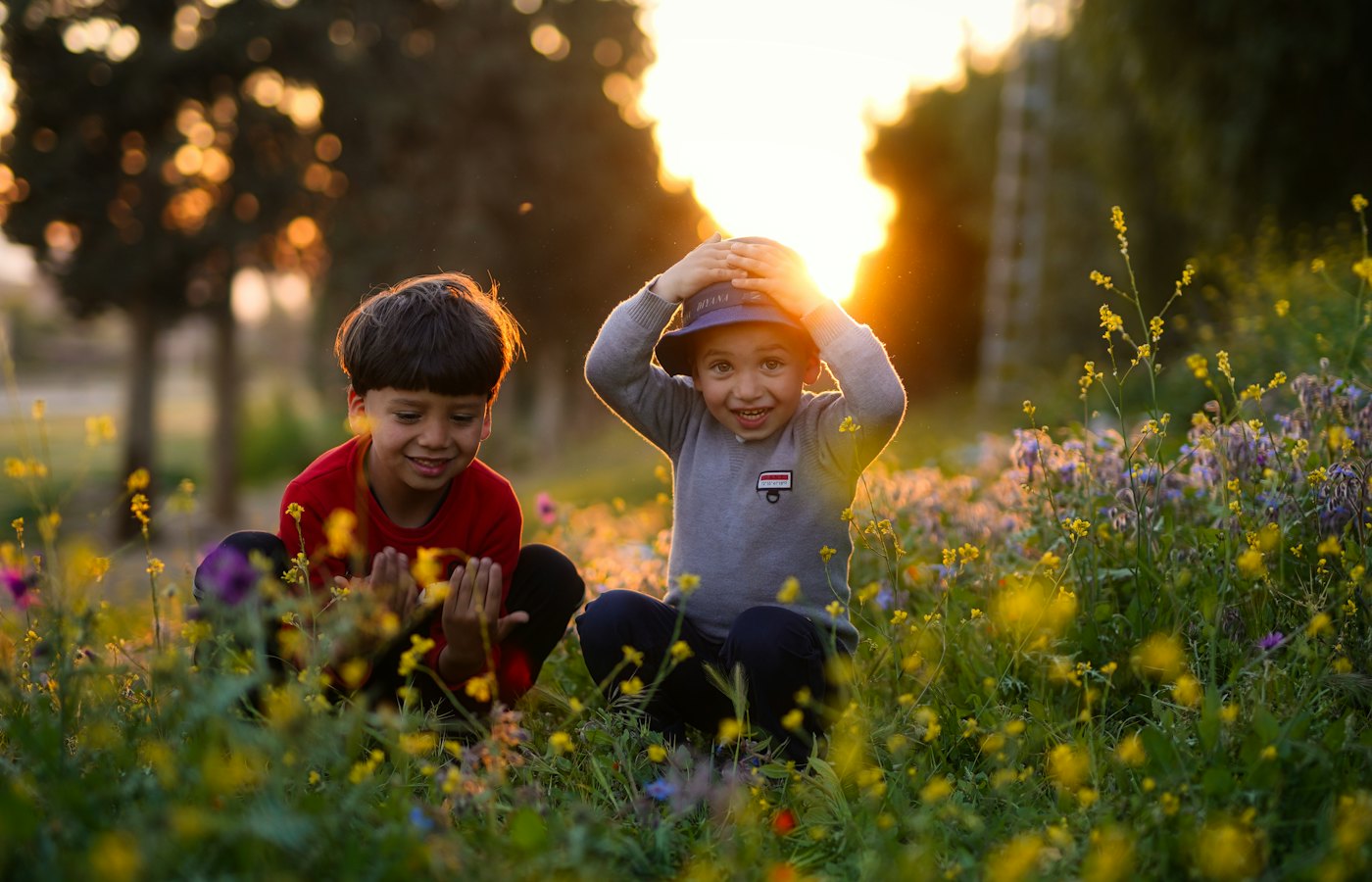 Two boys laughing in a field of wildflowers at sunset